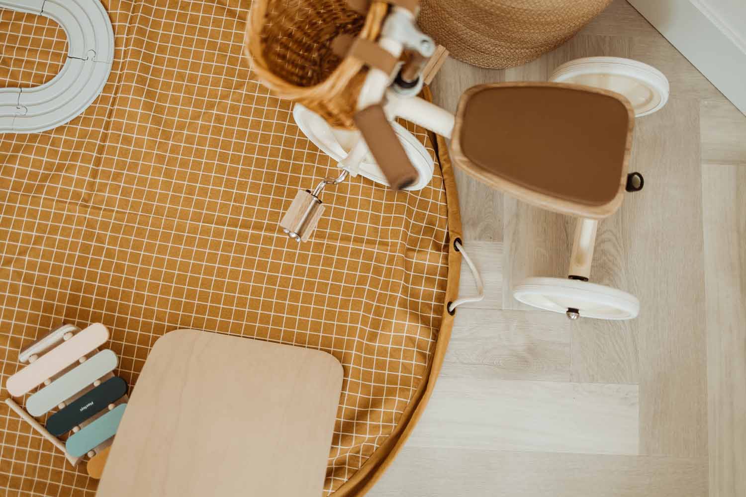 Playandgo_storage_bag_organic_grid_mustard_on_floor_with_wooden_tricycle